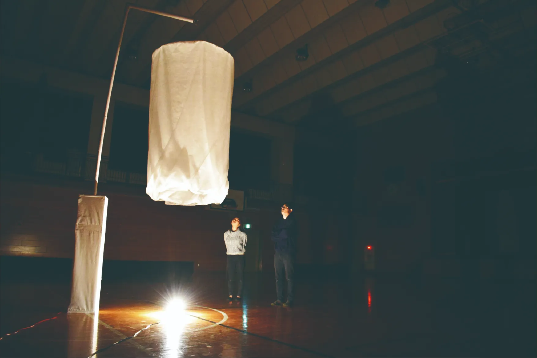 装置を二人の女性と男性が見上げる画像